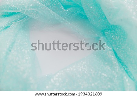 Close up picture of blue mint tulle fabric with glitter on the white background. Abstract wallpaper for the fashion industry with copy space for text. Round shape for text, flat lay.