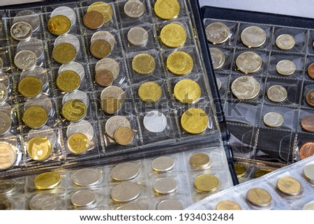 Сoins are arranged in transparent blisters. Page from album full with old coins . Coin storage method. Numismatic collection. Focus in background. Close-up. Copy space. Royalty-Free Stock Photo #1934032484