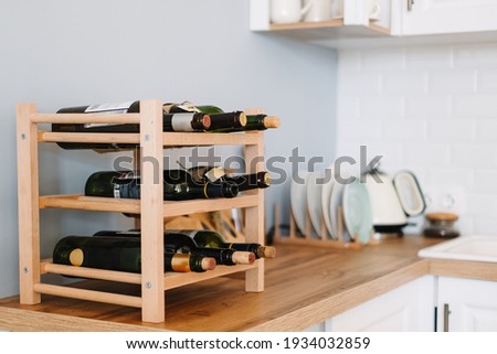 Wooden wine supply with bottles on table in modern kitchen. Royalty-Free Stock Photo #1934032859