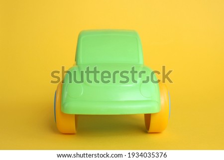 green toy car stands on yellow background