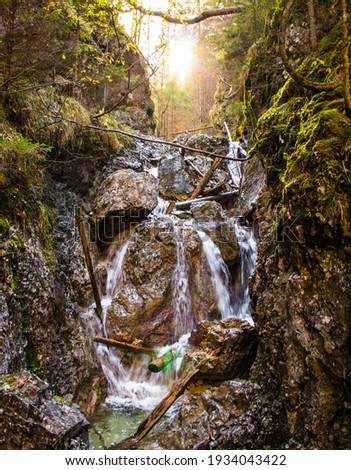Small waterfall in gorge in forest with sun in the background