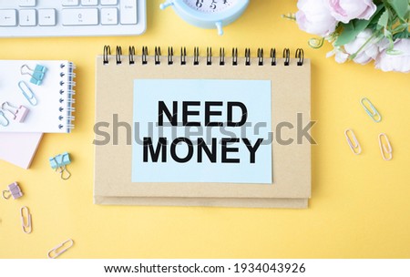 Text Need Money in the notebook on the yellow background