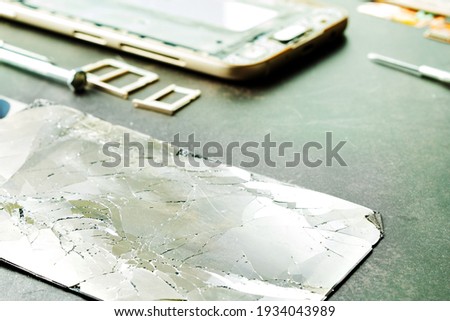 Broken phone display on a dark background, close-up, phone repair
