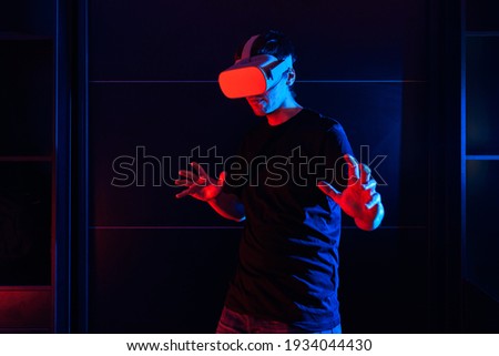 Gamer boy using virtual reality glasses having fun at home with cool lights.