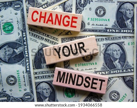Wooden blocks form the text 'change your mindset' on beautiful background from dollar bills. Concept.