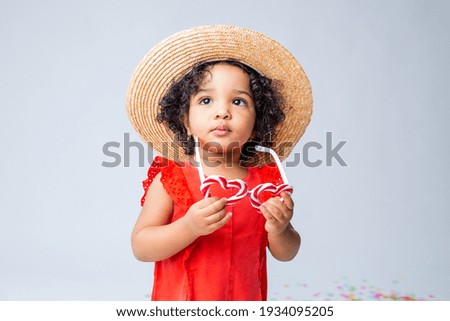 little African American girl in red summer clothes and a straw hat on a white background