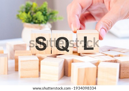 Businesswoman hand holding SQL word with wooden cube block. SQL short for structured query language, concepts