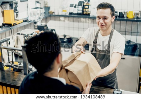 The customer buys lunch food with them in a paper cup. A confident man of European appearance in a restaurant. He works on a laptop computer and keeps a report on the expenses of his business statistics Royalty-Free Stock Photo #1934108489