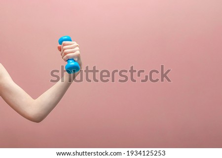 Boy's hand holding a dumbbell on a pink background.Sports concept. Banner ,postcard and panoramic edition. copy space text