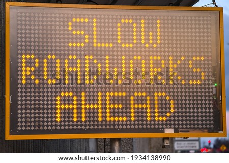 LED traffic control road sign solar powered message board mobile trailer variable message signs displaying Slow Roadworks Ahead along motorway in Dublin, Ireland