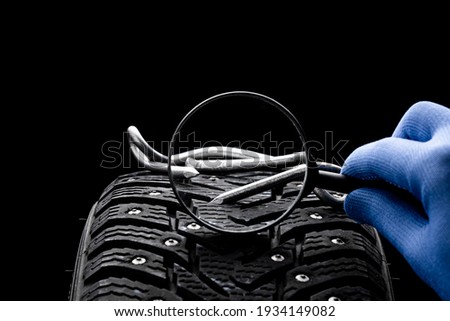 huge nail on a tyre over black background. studio shot. copy space. repair car tire concept. trouble on path conceptual.
