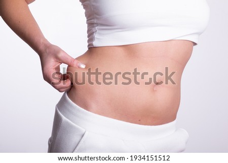 A woman using pinch test as one of the methods for measuring body fat on belly