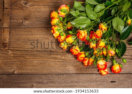 Bouquet of bright yellow-orange roses on old wooden table. Festive gift, greeting card for Easter, Birthday, Valentines Day or Wedding. Holiday concept, a place for text, top view