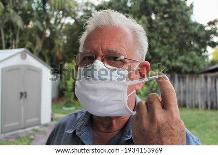 Elderly Hispanic man wearing double or two face mask to protect from coronavirus or covid-19 outbreak - concept of safety, healthcare, medical and hygiene.