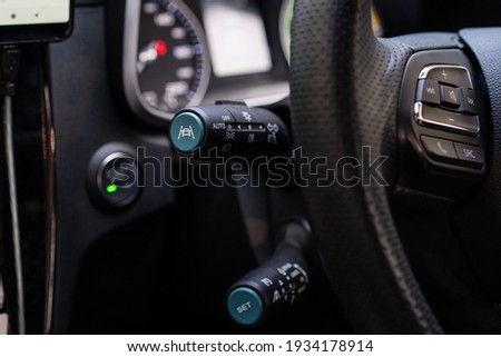 Unrecognizable man driver activating the adaptive cruise control or steering assistant on the control stick behind steering wheel  in electric vehicle - EV. Driving Assist system in modern car. Royalty-Free Stock Photo #1934178914