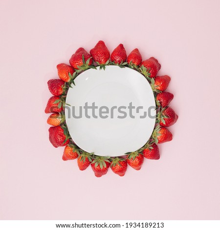 Organic ripe strawberries on a pastel pink background. A frame of fresh strawberries, inside a white plate. Flat lying, top view, copy space.