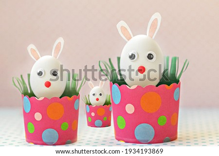 White chicken eggs with bunny ears in eco friendly pink paper trays, boxes. Family.Happy Easter holiday concept
