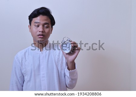 Sleepy guy and alarm clock in hand. Bearded man with alarm clock. Sleep complex biological process that helps process new information, stay healthy and feel rested. Stressed man alarm clock.