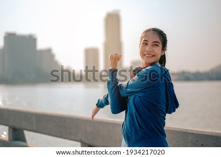 Young asian women drink water and stand to rest after jogging a morning workout in the city. A city that lives healthy in the capital. Exercise, fitness, jogging, running, lifestyle, healthy concept.