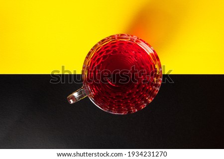 Red tea in cup isolated on black and yellow background