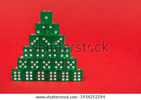 A group of green cubes lies in the form of a pyramid or stacks in ascending order on a red background of the text space: a Christmas tree made of green game cubes