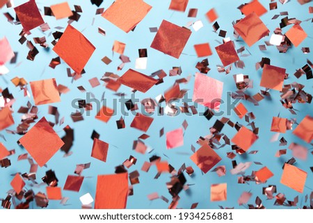 Shiny pink confetti falling down on light blue background