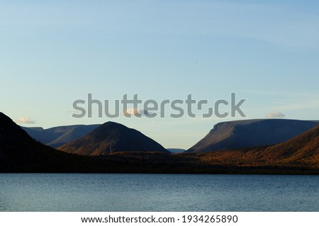 View of the high mountains and the wide lake in Kirovsk. Autumn picture of beautiful mountains, blue sky and blue lake. Kirovsk, Khibiny, Murmansk region. Wallpaper.