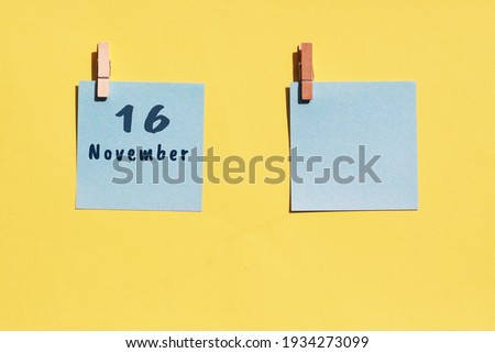 16 november. 16th day of the month, calendar date. Two blue sheets for writing on a yellow background. Top view, copy space. Autumn month, day of the year concept.