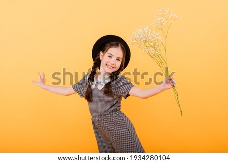 Funny child girl smiling with bouquet of flowers on coloured background