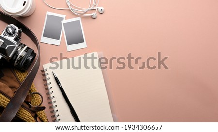 Top view of pink table with notebook, pen, camera, photo frame, bag and copy space, mock up scene 