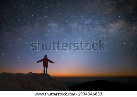 Silhouette of young traveler and backpacker watched the star and milky way alone on top of the mountain. He enjoyed traveling and was successful when he reached the summit.