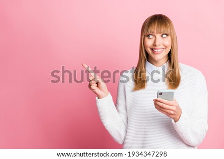 Photo of young cheerful smiling good mood lovely pretty woman point finger copyspace use phone isolated on pink color background