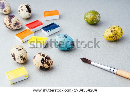 Coloring eggs for Easter. Paints, brushes, quail eggs on a gray background. Preparation for the celebration of Easter, traditional decorations, background. Creative concept.