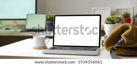 Close up view of workspace with mock up laptop, bag, cup and decorations in blurred office room background, clipping path