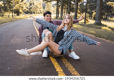 Happy teenage friends sitting on a skateboard .