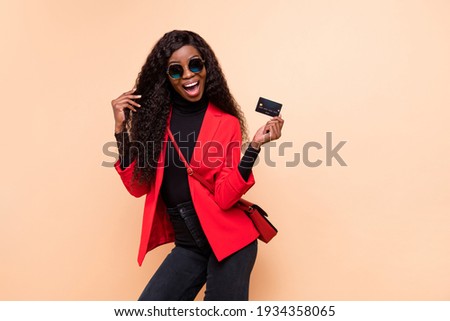Photo of amazed happy dark skin woman hold credit card wear bag sunglass isolated on beige color background