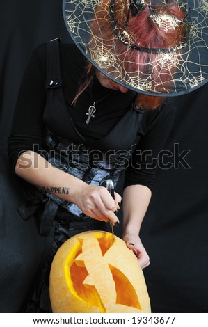 witch prepare pumpkin on black background