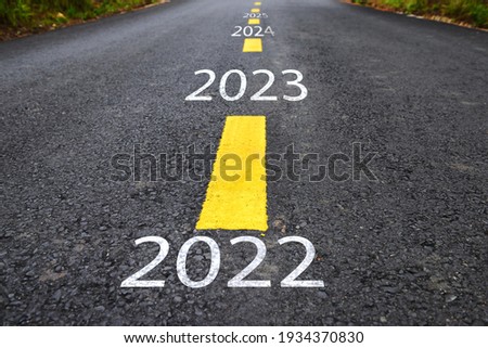 Number of 2022 to 2025 on asphalt road with yellow line marking on road surface. Happy new year concept and productive idea