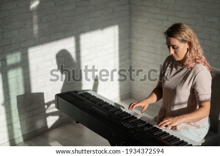 Caucasian woman playing on electronic synthesizer.