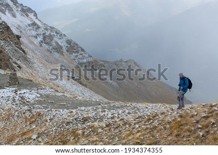 Solo traveler walks along a mountain valley. New reality, isolation, lonely journey. Spring view trekking in the fresh air. Back view of man with a backpack. Scenic landscape picture with copy space