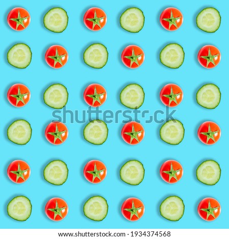 Top view of fresh cucumber slices and red cherry tomatoes isolated on blue background. Fresh vegetables seamless pattern. Flat lay composition, pop art