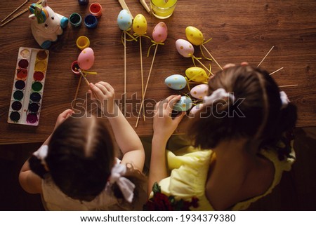 Happy easter. Children paint eggs with colorful paints for Easter. They sit at the table. View from above