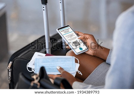 Close up of black hands of woman at airport checking her valid digital vaccination passport for covid19 while holding face mask and boarding pass. Businesswoman displaying health passport for covid-19 Royalty-Free Stock Photo #1934389793