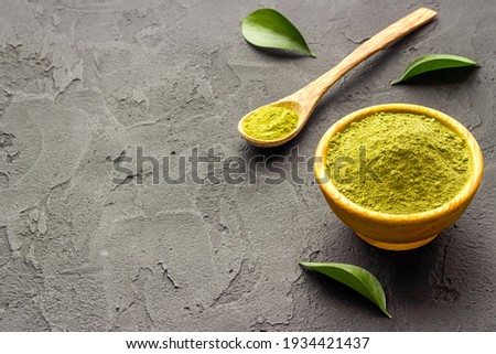 Henna powder in wooden bowl with green leaves. Herbal natural hair dye