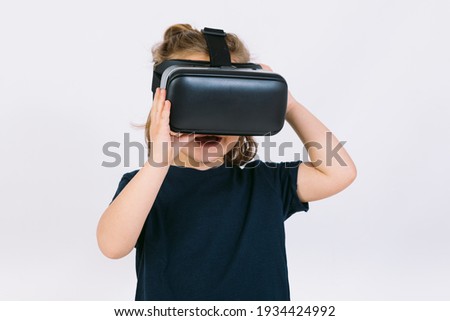 Little girl wearing virtual reality glasses with hands hold goggles on white background