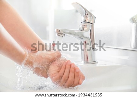 Woman use soap and washing hands rubbing with soap under the water tap. Hygiene new normal concept to stop spreading coronavirus or influenza virus in hospital or public wash room. Royalty-Free Stock Photo #1934431535