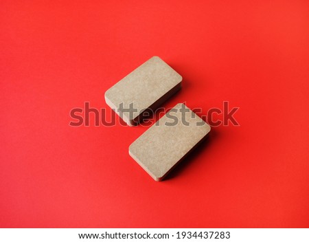 Blank kraft business cards on red paper background. Template for graphic designers portfolios.