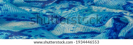 blue fabric with snakeskin pattern, background texture of bright blue fabric close up. background, texture, pattern