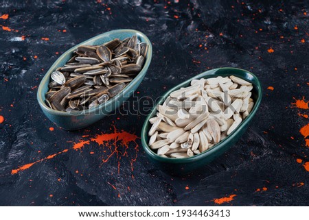 On navy blue table, various kinds of sunflower seeds on plates. High quality photo