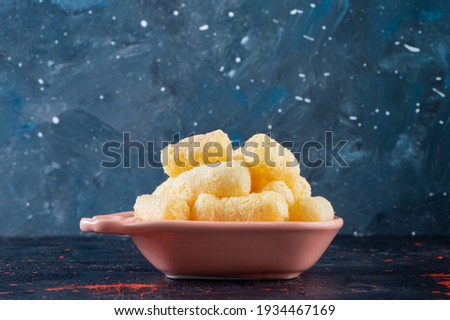 On blue background purple bowl with sweet corn sticks. High quality photo